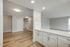 Bright and spacious apartment interior with elegant hardwood flooring, modern recessed lighting, and a sleek open kitchen with white cabinetry.