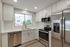 Modern kitchen with sleek stainless steel appliances, white cabinetry, and a bright window view.