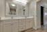 Elegant bathroom with dual sinks, modern white cabinetry, and stylish lighting, ideal for a serene ambiance.