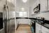 Bright, modern kitchen with sleek stainless steel appliances, elegant white cabinetry, and polished black countertops offering ample space and style.