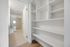 Bright and modern hallway featuring built-in shelving and a view into a stylish bathroom with a glass-enclosed shower.