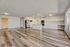 Spacious open-plan kitchen and living area with elegant wood flooring and modern white cabinetry, featuring sleek stainless steel appliances and ample natural light.
