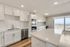 Modern kitchen with sleek white cabinetry, stainless steel appliances, and panoramic cityscape views through large windows.
