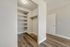 Chic walk-in closet featuring sleek shelving and modern lighting on elegant wood flooring.