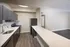Modern kitchen with sleek dark cabinetry, stainless steel appliances, and elegant countertops opening to a spacious living area with wood flooring.