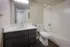 Modern bathroom with sleek vanity, large mirror, and pristine bathtub, exuding elegance and comfort.
