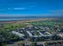 Aerial view of a vibrant apartment community surrounded by lush greenery, lake, and cityscape, offering an idyllic blend of nature and urban living.