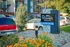 Inviting leasing office sign at Raven apartment complex, complemented by vibrant flowers and greenery. Modern building and ample parking visible in the background.