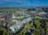 Breathtaking aerial view of a modern residential complex surrounded by lush greenery, showcasing vibrant apartments and nearby urban architecture.