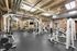 Industrial-designed fitness center with modern weight-lifting machines, free weights, and exposed brick walls.