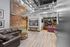 Modern industrial-style living area featuring exposed brick walls, sleek leather couches, and chic metal accents, perfect for urban living.