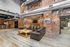 Chic industrial loft-style living room with exposed brick walls, metal ductwork, and modern furnishings.