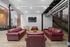 Loft-style living room with exposed brick walls, sleek industrial pipes, and modern red leather sofas.