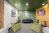 Chic and inviting lounge area with modern decor, featuring a black leather sofa, two green chairs, and ambient art on the walls.