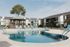 Inviting apartment community with a sparkling pool, stylish lounge chairs, and charming gazebo set against modern buildings and lush greenery.