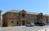 Charming two-story apartment complex with elegant arches and convenient parking spaces in a sunlit setting.
