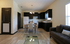 Inviting open-plan living space featuring a chic kitchen with dark cabinets and a cozy dining area, complemented by a sleek sofa and warm lighting.