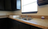 Modern kitchen featuring sleek granite countertops, a double sink, and elegant dark cabinetry.