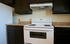 Modern kitchen featuring sleek dark cabinets, pristine white stove, and elegant granite countertops.