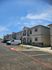 Charming apartment complex with modern design, highlighting spacious balconies and ample parking under a bright blue sky.
