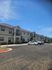 Charming two-story apartment complex with spacious parking, showcasing modern design and inviting exterior under a bright blue sky.