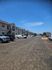 Charming apartment complex with spacious parking and elegant exterior design under a bright blue sky.