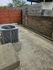 Cozy outdoor patio with modern stone wall and natural wooden fencing, featuring a compact air conditioning unit, ideal for private relaxation.
