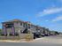 Charming apartment complex with modern architecture, ample parking, and clear blue skies enhancing the welcoming ambiance.
