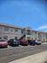 Charming two-story apartment complex with neatly arranged parking spaces under a clear blue sky.