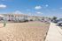 Charming apartment complex with modern architecture, ample parking, and a tranquil setting under a bright blue sky.