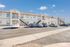 Modern apartment complex with convenient outdoor stair access, ample parking, and elegant architectural design under a clear blue sky.