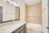Modern bathroom with elegant granite countertop, large mirror, and luxurious tiled shower.