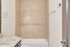 Elegant bathroom featuring a modern ceramic-tiled shower and granite countertop in a serene color palette.