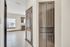 Bright apartment entryway with modern tile flooring, sleek dark wood cabinetry, and a glimpse of a sunlit kitchen beyond.