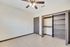 Bright and spacious room featuring elegant tiled flooring, a sleek ceiling fan, and ample closet space with dark wood accents.