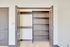 Spacious and well-lit closet with elegant double doors, offering ample shelving and storage space on a sleek tile floor.