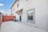 Charming exterior of a two-story apartment with modern design, featuring a private fenced patio and bright windows under a clear blue sky.