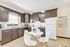 Chic modern kitchen with dark wood cabinets, white appliances, and a cozy round dining table set for four.