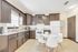 Bright kitchen with sleek dark cabinets, marble countertops, stainless appliances, and a charming dining area with modern white chairs.