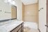 Modern bathroom with granite countertop, large mirror, elegant tiling, and a spacious bathtub.