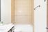 Elegant bathroom featuring a tiled shower-tub combo with stylish beige tiles and a sleek granite countertop.
