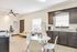 Inviting open-concept kitchen and living area with stylish dark cabinetry, granite countertops, and modern dining set, perfect for comfortable living and entertaining.