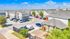 Charming community of modern townhouses with ample parking and manicured landscaping under a sunny blue sky.