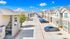 Modern apartment complex with well-maintained parking area, bright exterior, and blue skies, offering a welcoming and vibrant living environment.