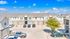 Bright and inviting apartment complex with modern architecture, ample parking, and lush greenery under a clear blue sky.