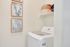 Modern laundry nook featuring a sleek white washing machine, stylish wicker basket, and elegant botanical wall art.