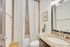 Elegant bathroom featuring a granite countertop, modern fixtures, and a stylish ceramic sink, complemented by a serene shower area with a light curtain and decorative plant for a refreshing ambiance.