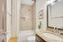 Elegant bathroom with a tiled shower, granite countertop, and stylish decor.