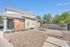 Charming single-story home with well-maintained exterior, featuring a private fenced yard and a cozy picnic area, set against a vibrant blue sky.