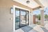 Inviting apartment entrance with stylish lighting and modern glass doors, surrounded by lush greenery and a sunny, serene outdoor space.